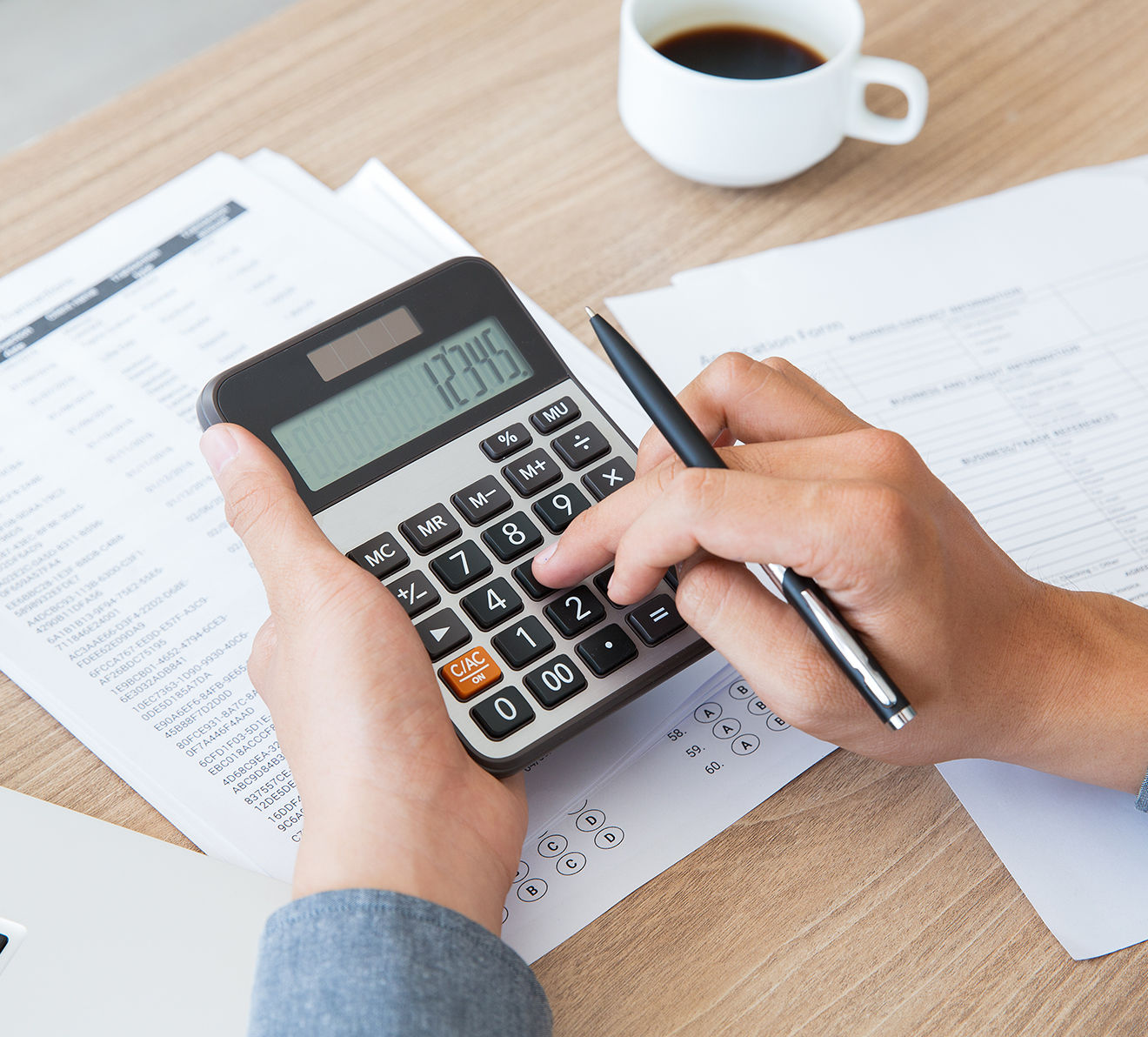 Hands using calculator with financial documents
