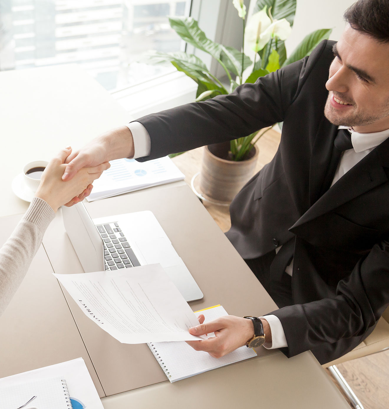Business handshake over laptop and documents